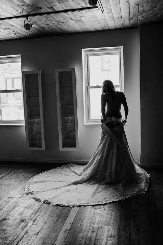 Bridal Boudoir in wedding gown looking out window