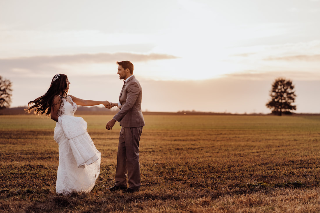 Couple dancing during sunset in field after wedding