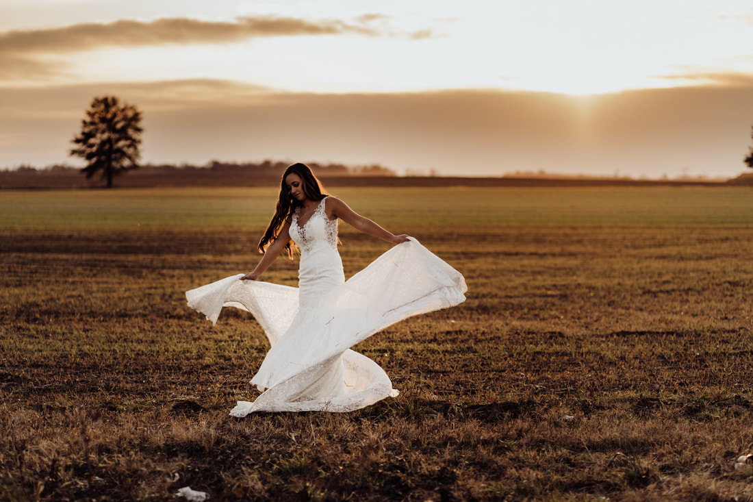 Bride dancing during sunset in field