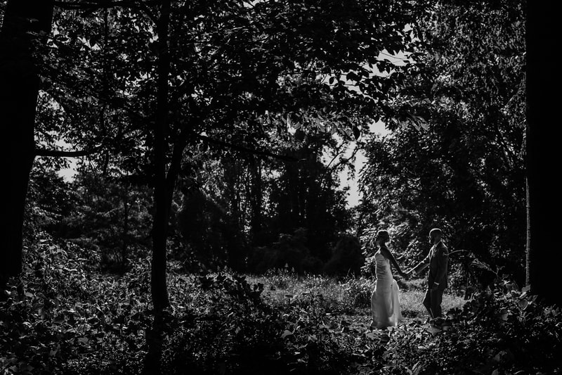Black and white foliage bride and groom walking in distance