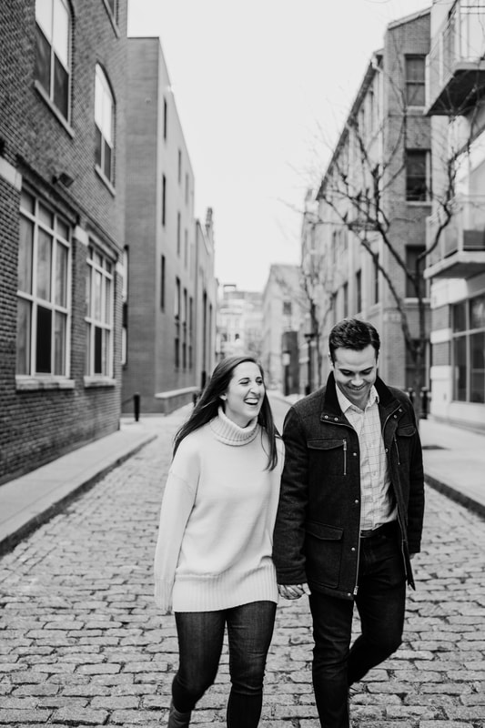 Black and white couple laughing while strolling down brick road