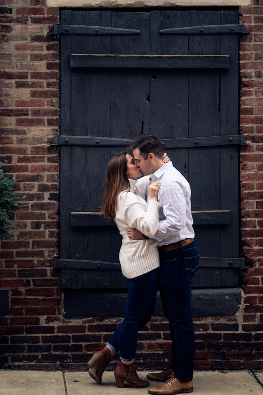 Couple kissing against black barn door with brick