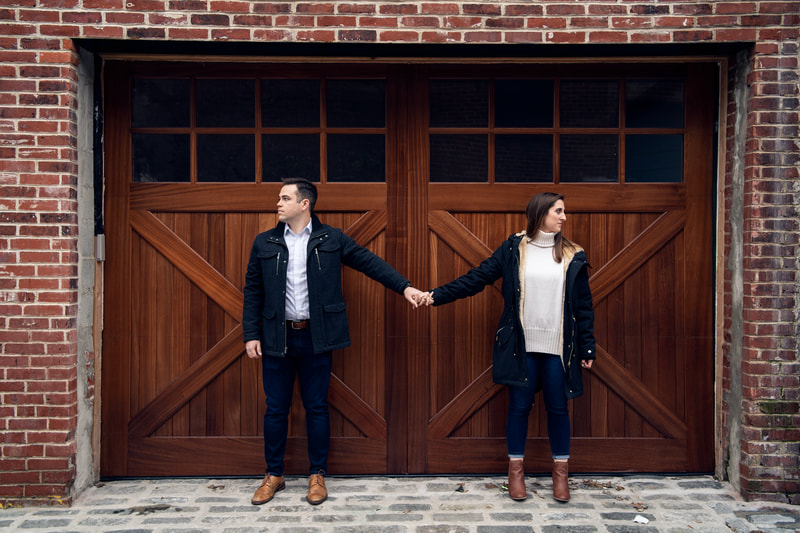 Couple holding hands looking in opposite directions against building doorway
