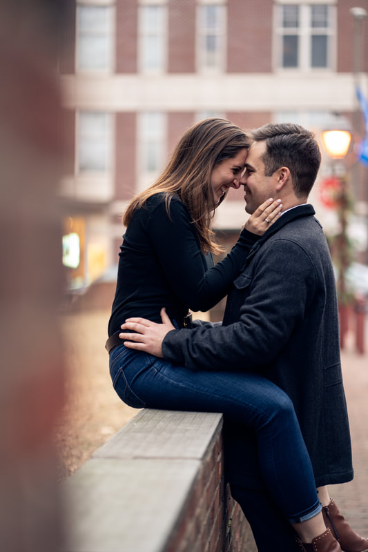 City couple about to kiss while sitting on railing