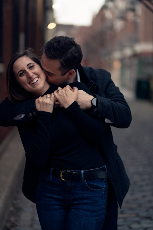 Fiance hugging bride to be from behind in city streets