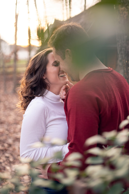 Couple laughing in fall behind foliage