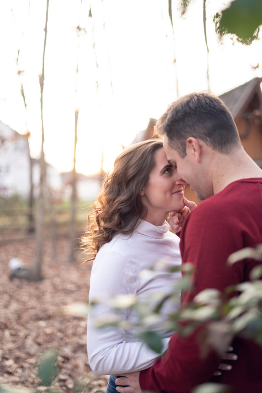 Fall bride to be looking up at fiance in front of cabin