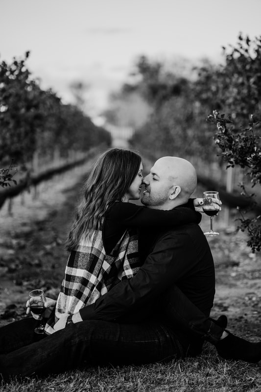 Black and white couple about to kiss drinking wine in vineyard