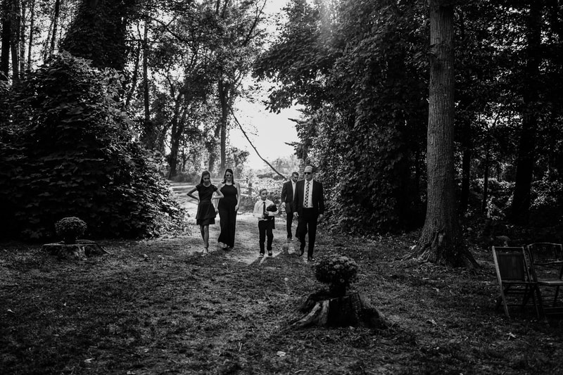 Black and white wedding party walking through woods