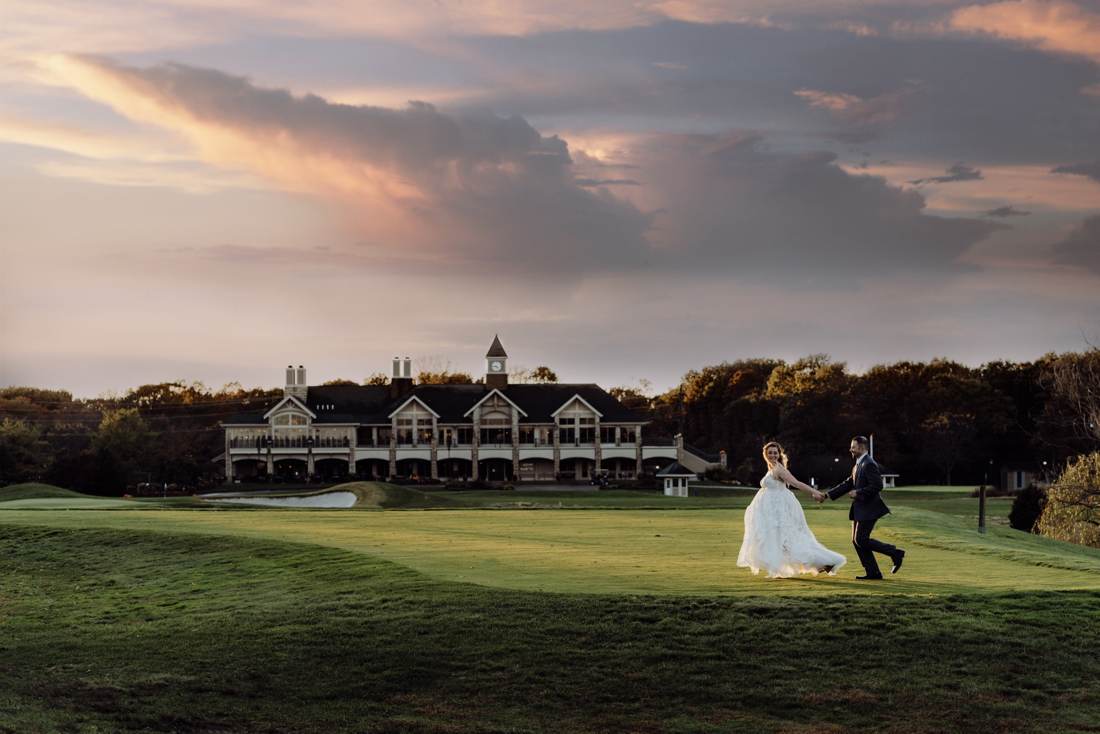 Couple running across golf course after wedding at Scotland Run Country Club at sunset